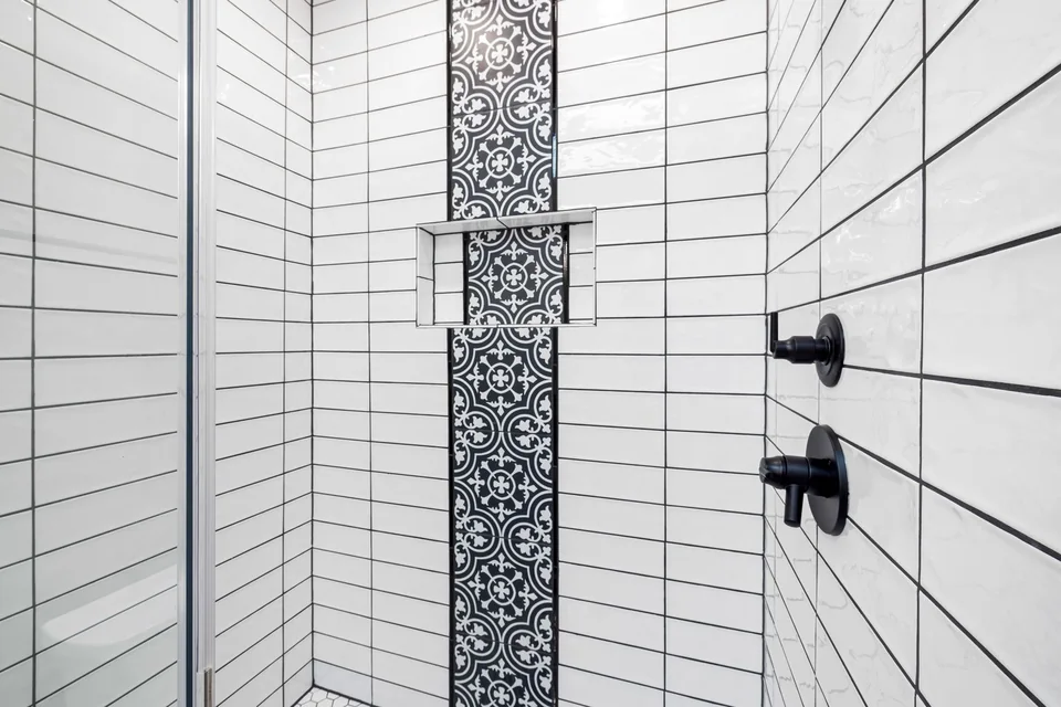 Douche carrelée de blanc avec une frise de carreaux à motifs