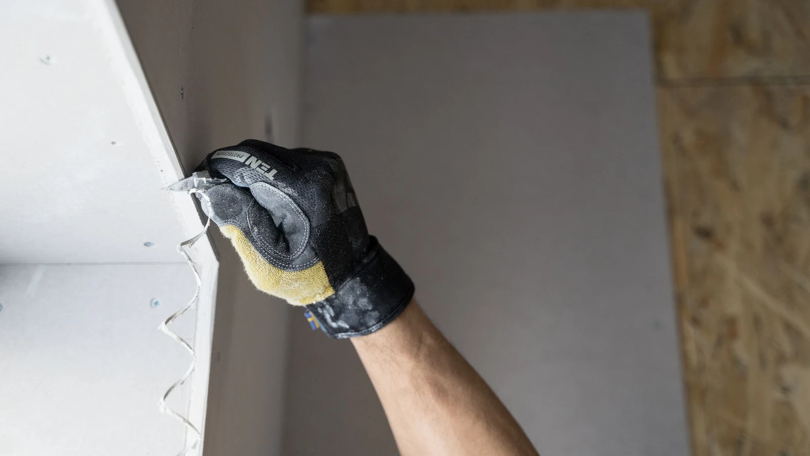 Main gantée lissant un joint entre deux plaques de plâtre