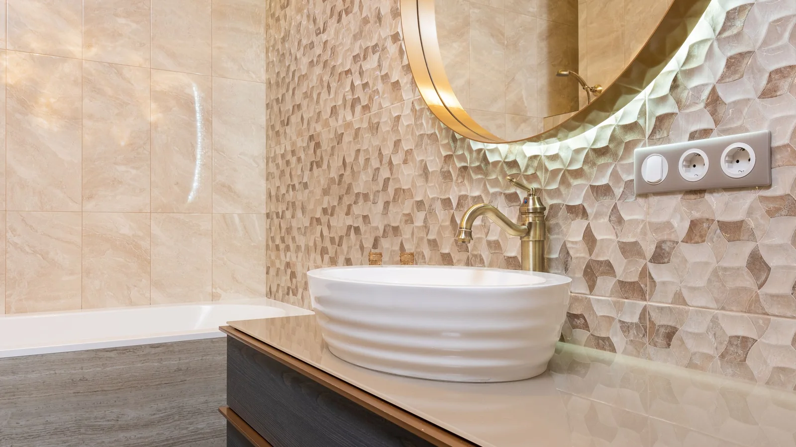 Salle de bains habillée de faïence beige en relief, vasque et miroir rond